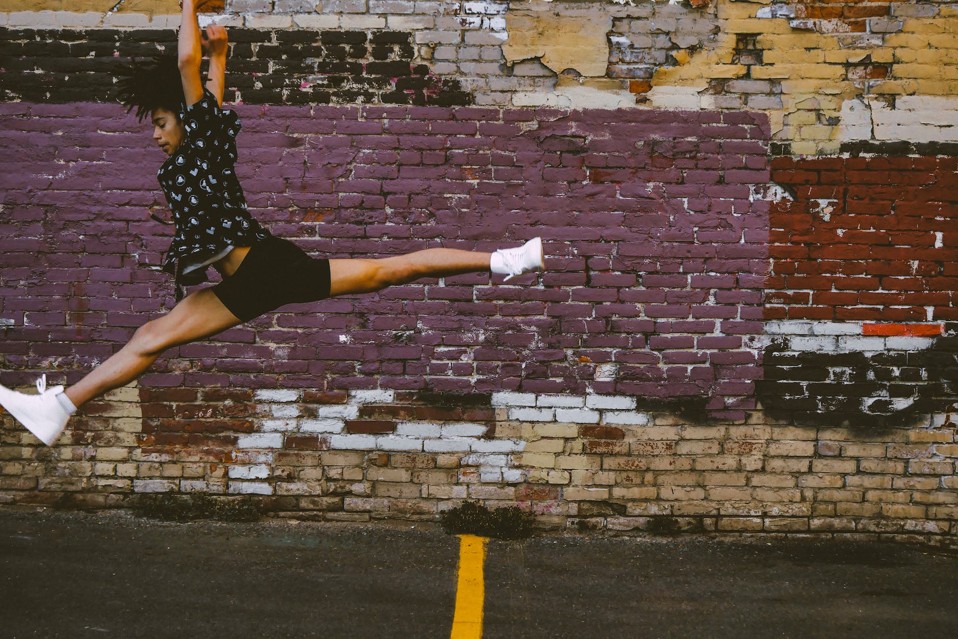 photo of person jumping near brick walls