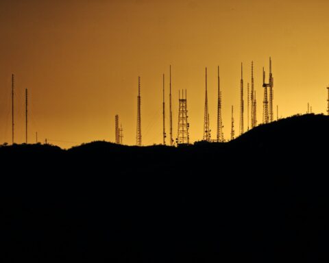 silhouette photo of transmission tower on hill