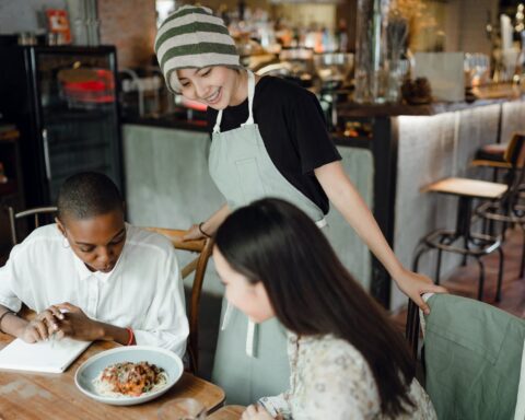 cheerful young asian waitress communicating with multiracial clients