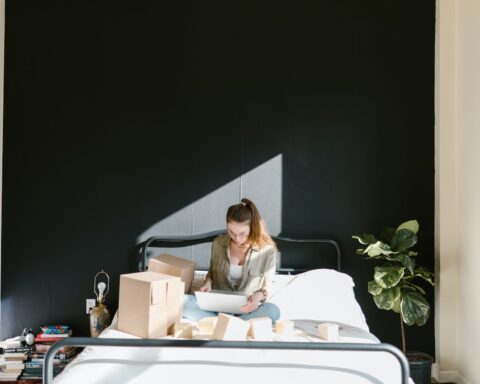 a woman using a laptop while in bed