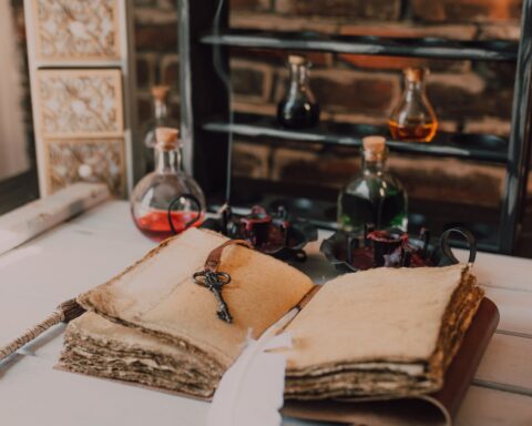 an old book and candles on wooden table with glass bottles