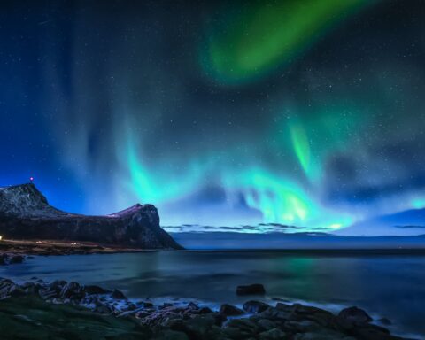 green aurora lights over rocky shore during night time