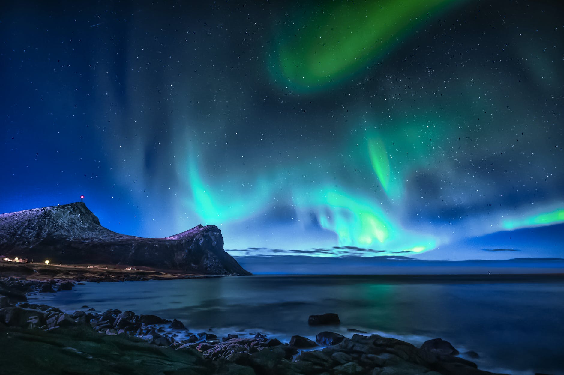 green aurora lights over rocky shore during night time