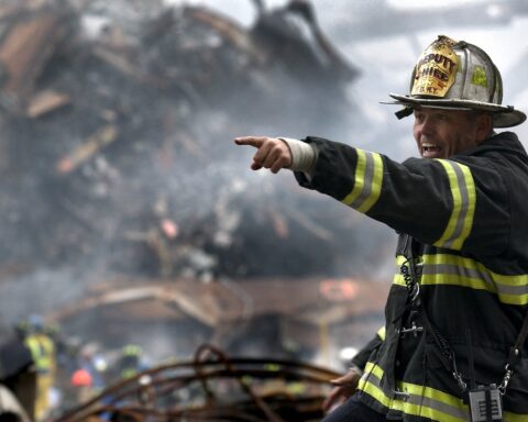 fire fighter wearing black and yellow uniform pointing for something