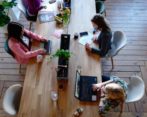 three woman sitting on white chair in front of table