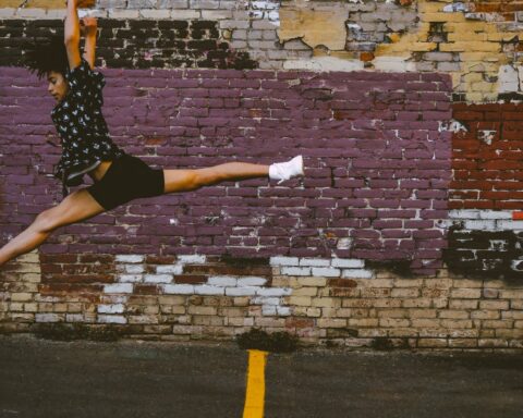 photo of person jumping near brick walls