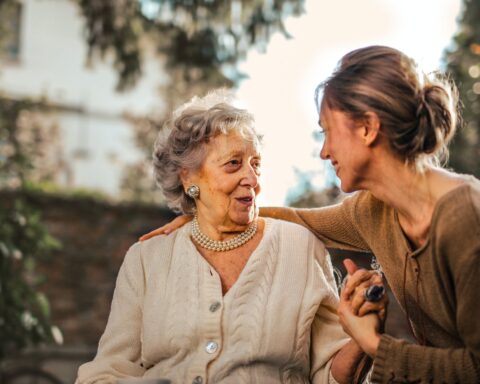 joyful adult daughter greeting happy surprised senior mother in garden