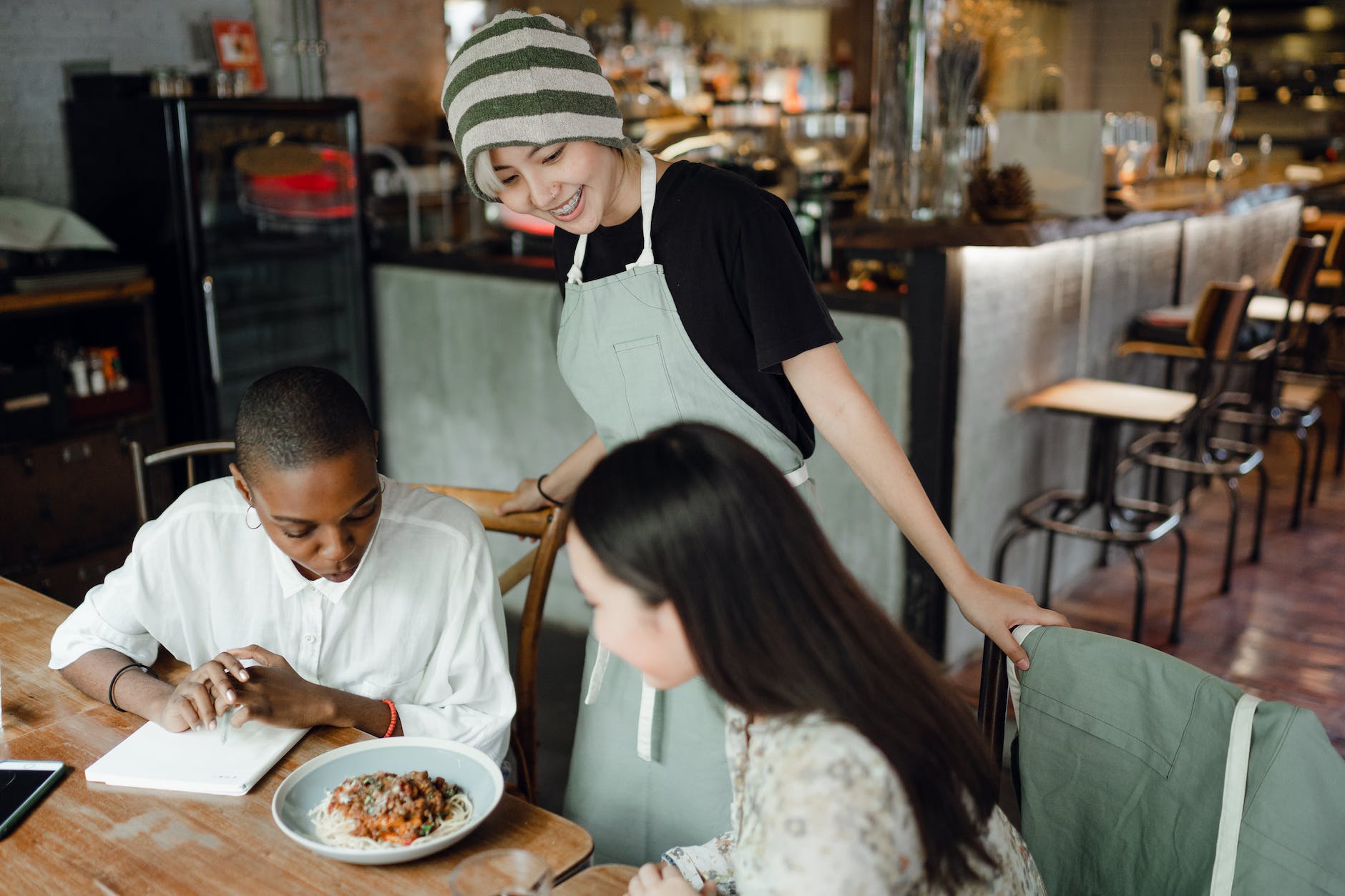 cheerful young asian waitress communicating with multiracial clients