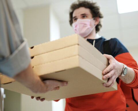 man wearing a face mask delivering pizza