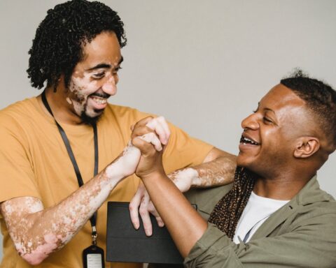 laughing black male colleagues clasping hands in excitement together