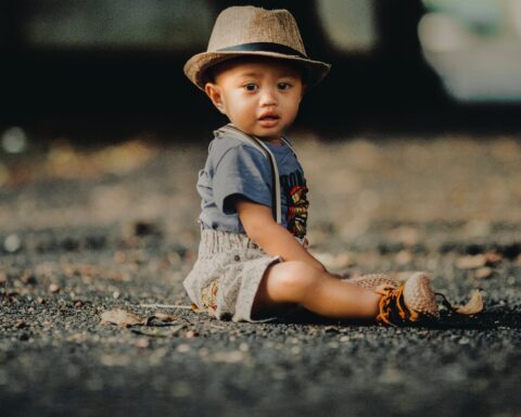 child in grey shorts sitting on road