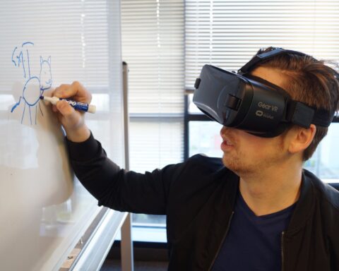 person wearing black vr box writing on white board