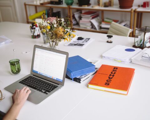 photo of orange book beside laptop