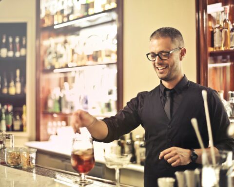 positive bartender preparing cocktail in pub