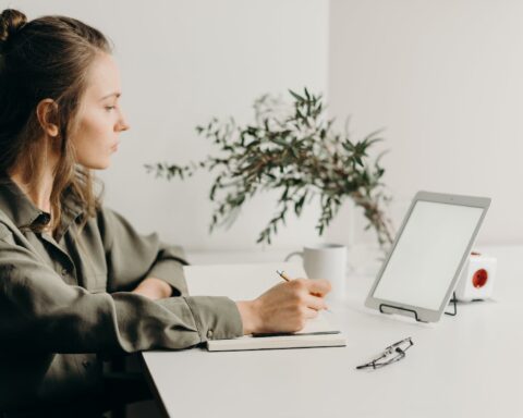 woman in gray coat using white laptop computer