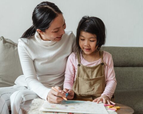 smiling woman tutoring ethnic girl at home