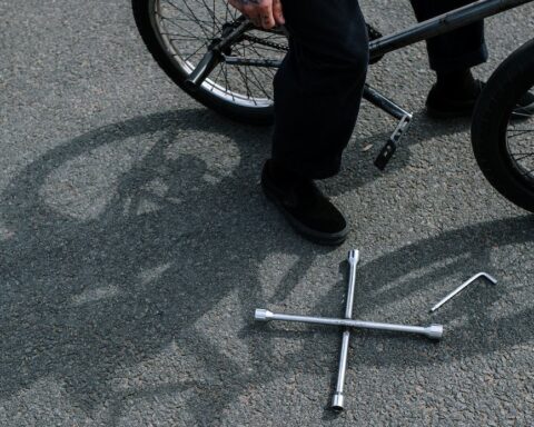 person in pants and black shoes on a bicycle near a tools