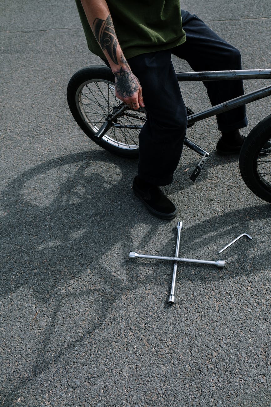 person in pants and black shoes on a bicycle near a tools