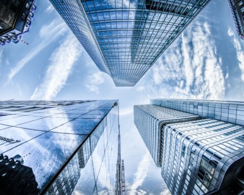 low angle photo of four high rise curtain wall buildings under white clouds and blue sky