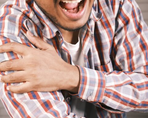 close up photo of an aching man holding his shoulder